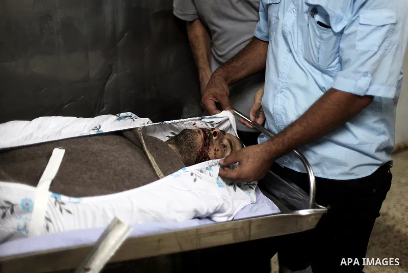 A Palestinian medic stands next to a dead body at a hospital in Gaza city on Aug 11, 2013. Israeli military forces have shot dead on Saturday an unarmed Palestinian man on the Gaza Strip border after he climbed over the...