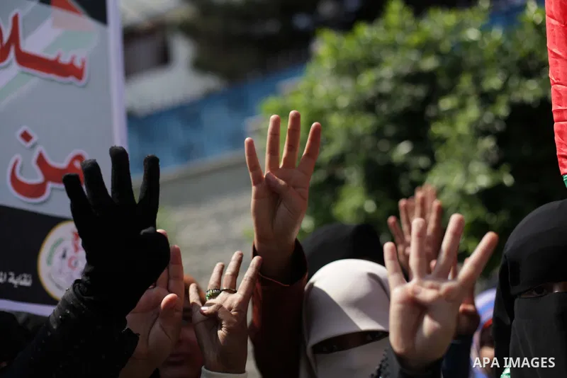 Palestinians hold up four fingers, a sign that protesters say symbolizes the Rabaah al-Adawiya mosque in Cairo, while waving an Egyptian flag during a protest supporting Egypt's ousted President Mohammed Morsi, in front...