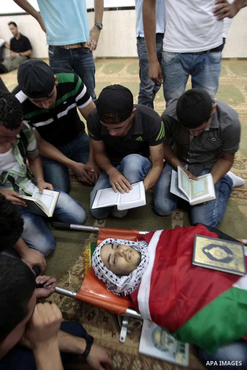 Palestinians mourn over the body of Majd Lahlouh during his funeral at Jenin refugee camp in the West Bank city of Jenin on August 20, 2013. Israeli troops shot dead the Palestinian youth and wounded two others during an...