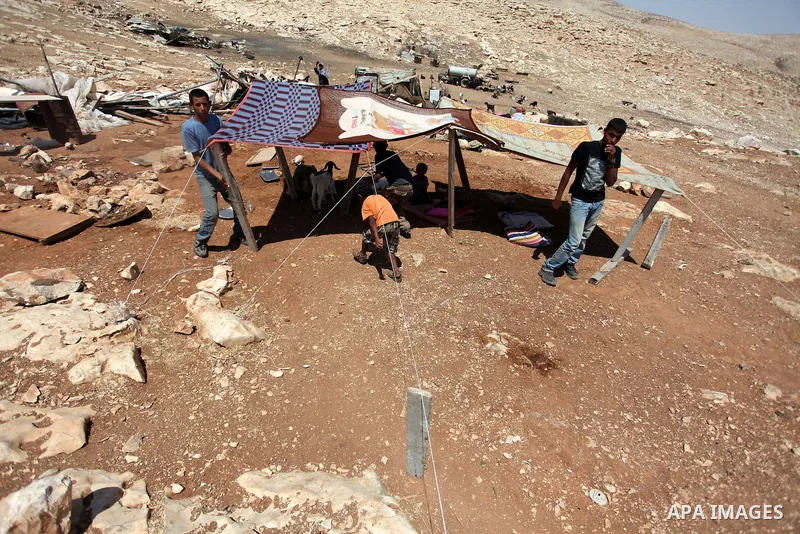 Palestinian Bedouins sit under a temporary tent after dismantled their tents by Israeli bulldozers under the pretext of building without permits at al-Baq'a camp near the West Bank city of Jericho, Aug 20, 2013. Photo by...