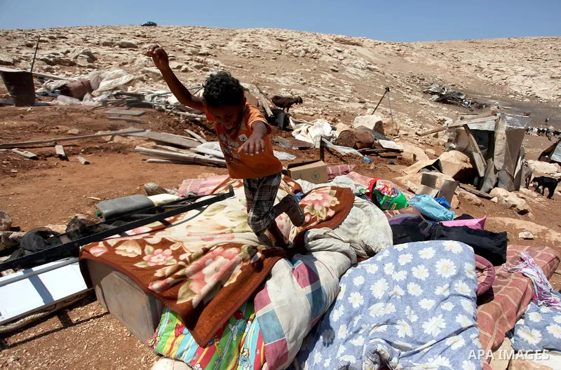 A Palestinian Bedouin boy plays on the rubble of his family damaged tent after it was dismantled by Israeli bulldozers under the pretext of building without permits at al-Baq'a camp near the West Bank city of Jericho, Au...