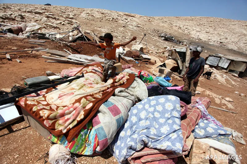 A Palestinian Bedouin boy plays on the rubble of his family damaged tent after it was dismantled by Israeli bulldozers under the pretext of building without permits at al-Baq'a camp near the West Bank city of Jericho, Au...