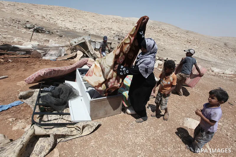 A Palestinian Bedouin woman searches in the rubble of her damaged tent after it was dismantled by Israeli bulldozers under the pretext of building without permits at al-Baq'a camp near the West Bank city of Jericho, Aug...