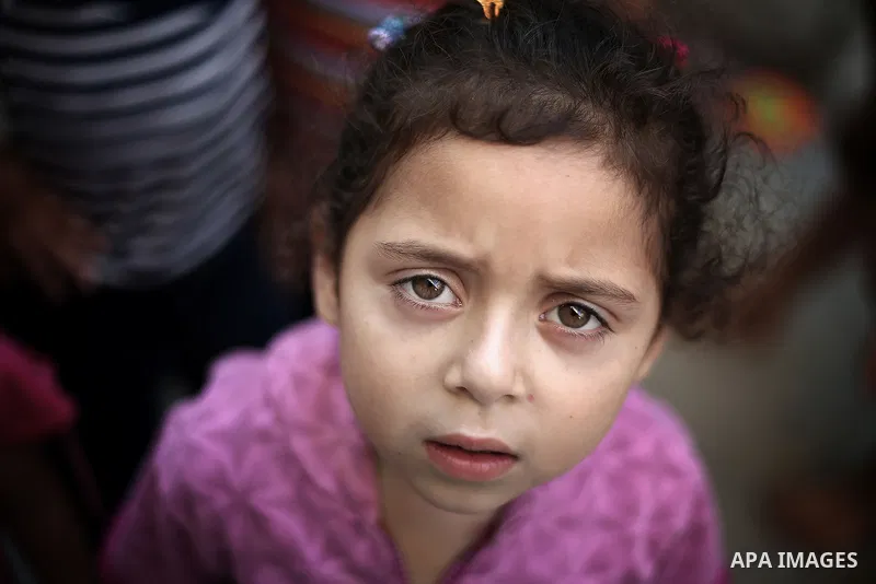 A picture taken on July 30, 2013 shows a Palestinian girl posing for a photograph as others playing outside their homes in Jabalia refugee camp northern Gaza Strip. Photo by Mahmoud Hamda