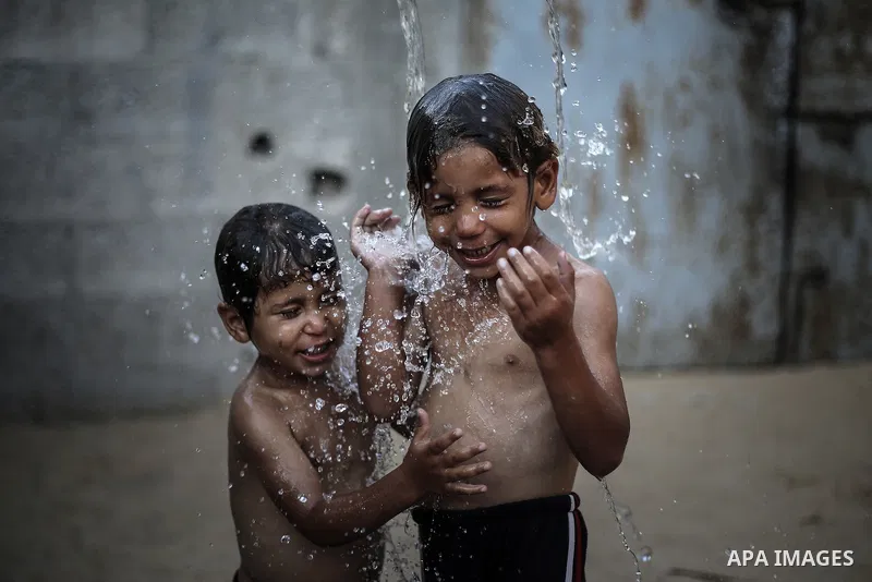 A picture taken on July 31, 2013 shows Palestinian children bathing in front of their home in Jabalia refugee camp northern Gaza Strip. Photo by Mahmoud Hamda