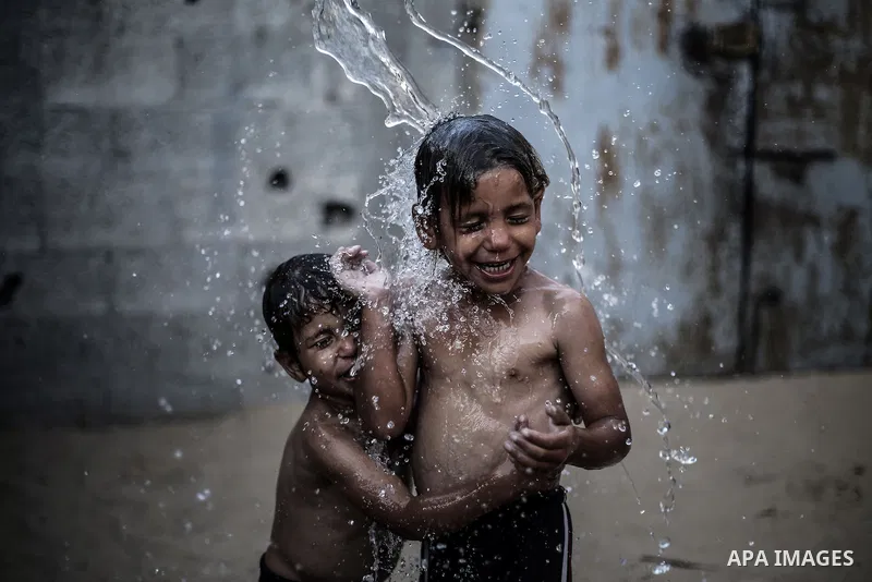 A picture taken on July 31, 2013 shows Palestinian children bathing in front of their home in Jabalia refugee camp northern Gaza Strip. Photo by Mahmoud Hamda