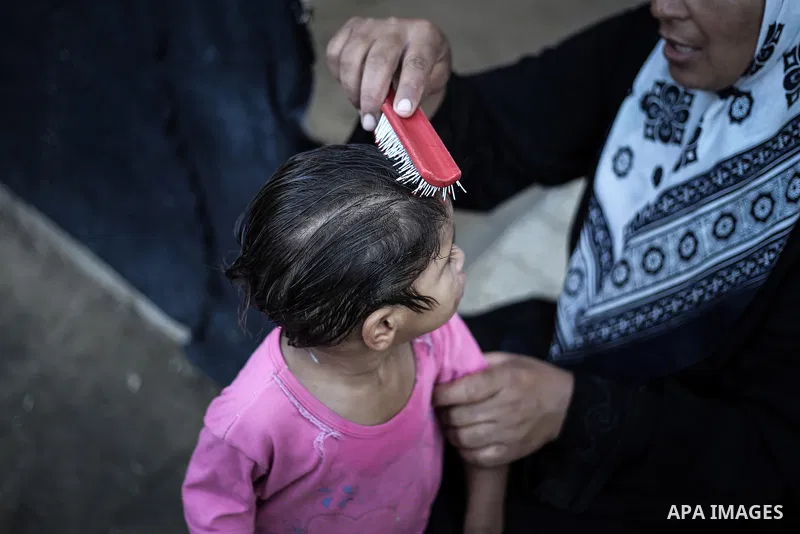 A picture taken on July 31, 2013 shows a Palestinian woman combing her daughter's hair in front of their home in Jabalia refugee camp northern Gaza Strip. Photo by Mahmoud Hamda