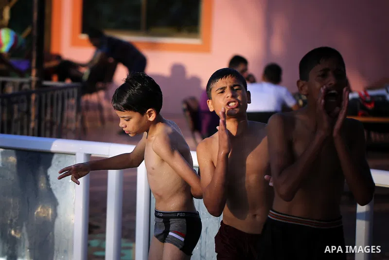 A picture taken on August 10, 2013 shows Palestinian boys swimming at a pool in Gaza City. Photo by Mahmoud Hamda