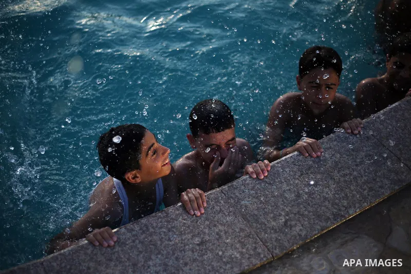 A picture taken on August 10, 2013 shows Palestinian boys swimming at a pool in Gaza City. Photo by Mahmoud Hamda