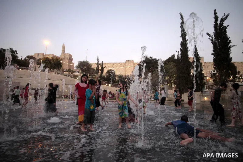 Palestinian children enjoy themselves with water in public parks founded by Israeli municipality near the wall of Jerusalem in the old town, on Aug. 20, 2013. Photo by Saeed Qaq
