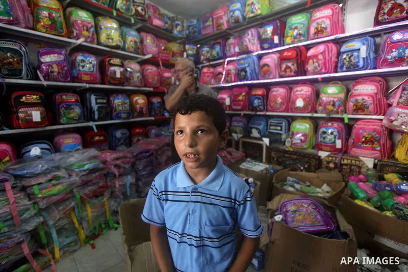 Palestinians shop during preperation for the new school year at a market in Gaza City on Aug 21, 2013. Palestinian Ministry of Education announced the 25 August is the first day of new school year in the West Bank and Ga...
