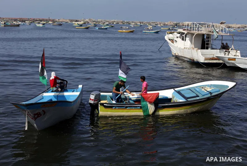 Palestinian fishermen hold banners flags during a rally inside the port of Gaza to protest on the Israeli siege on the Gaza Strip and the five-year anniversary of the entry of first two ships solidarity with Gaza, in Gaz...