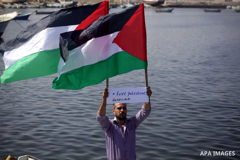 Palestinian fishermen hold banners flags during a rally inside the port of Gaza to protest on the Israeli siege on the Gaza Strip and the five-year anniversary of the entry of first two ships solidarity with Gaza, in Gaz...