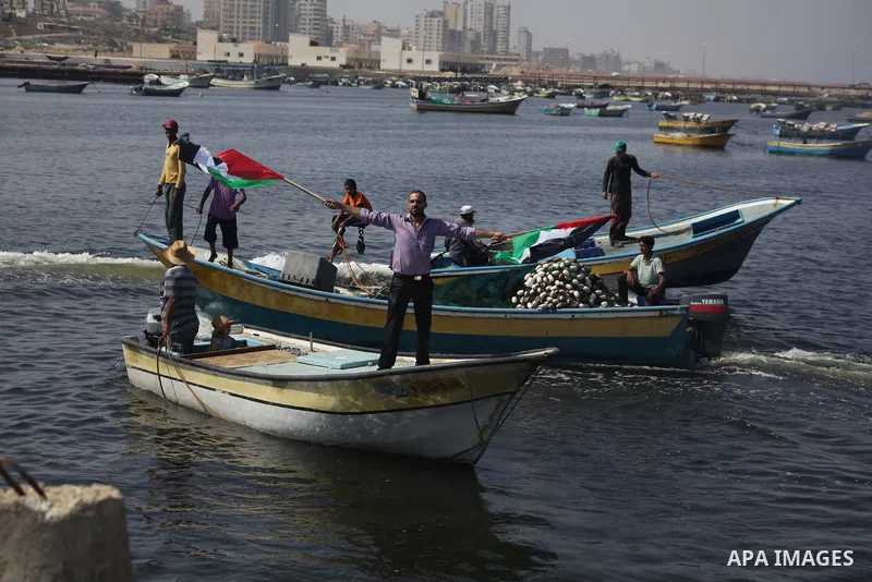 Palestinian fishermen hold banners flags during a rally inside the port of Gaza to protest on the Israeli siege on the Gaza Strip and the five-year anniversary of the entry of first two ships solidarity with Gaza, in Gaz...