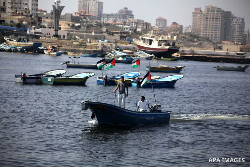 Palestinian fishermen hold banners flags during a rally inside the port of Gaza to protest on the Israeli siege on the Gaza Strip and the five-year anniversary of the entry of first two ships solidarity with Gaza, in Gaz...