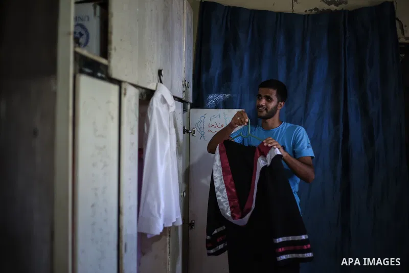 Fadi al-Shami, 21, a Palestinian blind youth, wears his graduation suit at his family home in Central Gaza Strip on Aug 17, 2013. al-Shami lost his sight after he was injured by an Israeli airstrike next to his family ho...