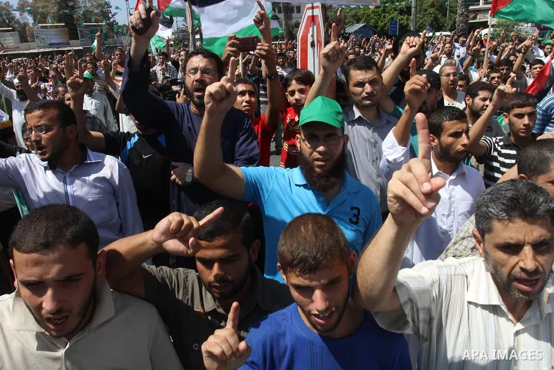 Palestinian supporters of Hamas and Islamic Jehad hold national flags during a protest against Palestinian-Israeli negotiations on August 23, 2013, in Gaza City. A senior Palestinian official accused on August 23 Israel...