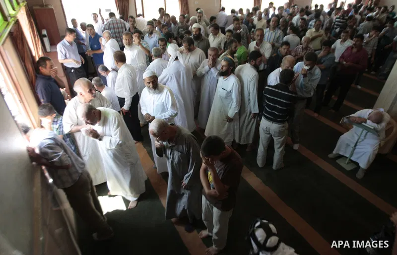 Palestinian worshipers cover their faces after inhaling tear gas fired by Israeli security forces at a mosque during Friday prayer in the village of Kfar Qaddum, near Nablus in the occupied West Bank on August 13, 2013....
