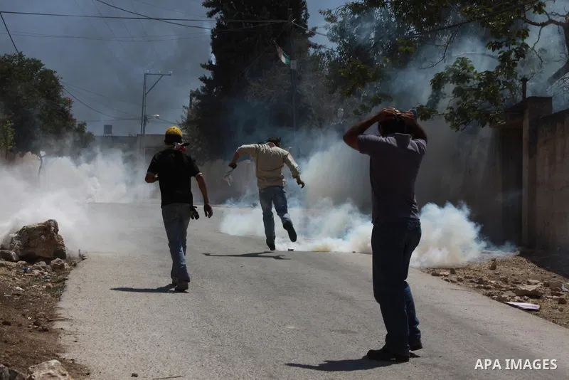 A Palestinian protester kicks back a tear gas canister fired by Israeli security forces during clashes following a protest against the expropriation of Palestinian land by Israel in the village of Kfar Qaddum, near Nablu...