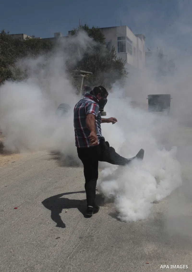A Palestinian protester kicks back a tear gas canister fired by Israeli security forces during clashes following a protest against the expropriation of Palestinian land by Israel in the village of Kfar Qaddum, near Nablu...