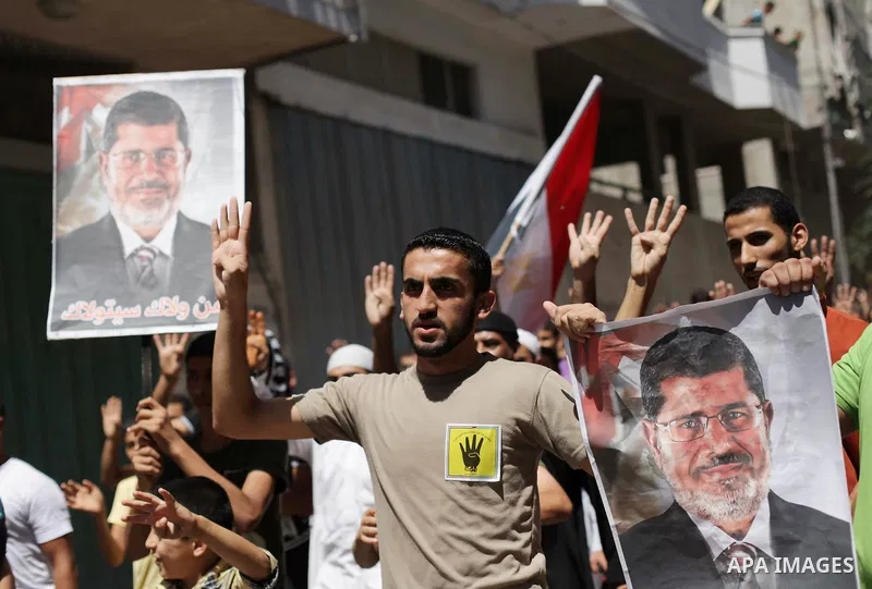 Palestinians hold Egyptian national flags, posters of ousted Egyptian President Mohamed Morsi and logos of four fingers, during a demonstration to support Morsi and denounce Syria's President Bashar al-Assad, in Al-Nusir...
