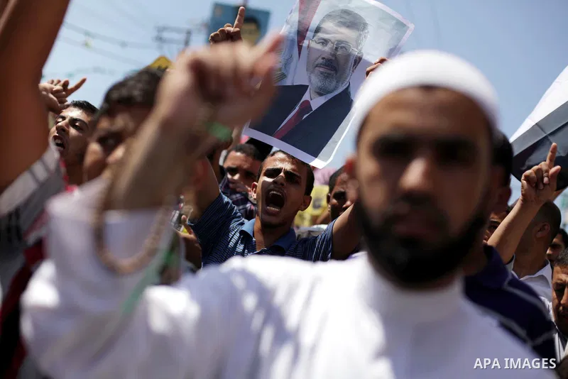 Palestinians hold up Egyptian national flags and posters of ousted Egyptian President Mohamed Morsi, during a demonstration to support Morsi and denounce Syria's President Bashar al-Assad, in Al-Nusirat refugee camp in c...
