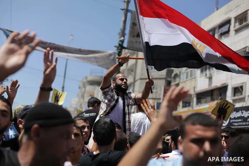 Palestinians hold Egyptian national flags, posters of ousted Egyptian President Mohamed Morsi and logos of four fingers, during a demonstration to support Morsi and denounce Syria's President Bashar al-Assad, in Al-Nusir...