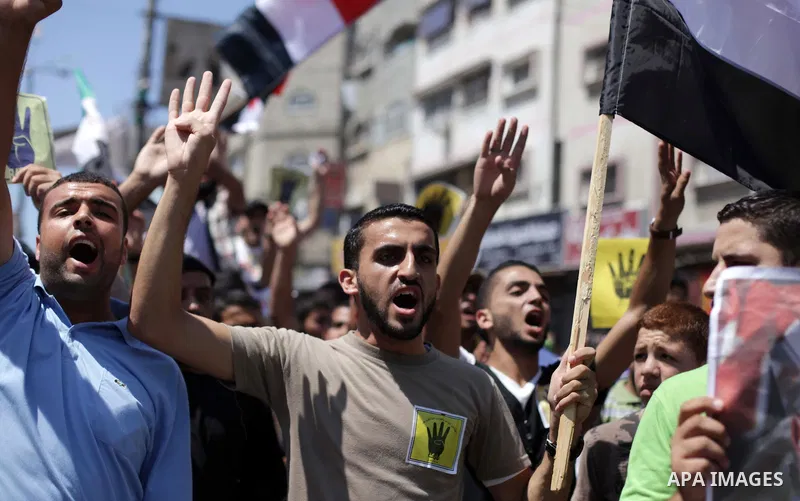 Palestinians hold Egyptian national flags, posters of ousted Egyptian President Mohamed Morsi and logos of four fingers, during a demonstration to support Morsi and denounce Syria's President Bashar al-Assad, in Al-Nusir...