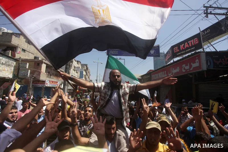 Palestinians hold up Egyptian national flags and posters of ousted Egyptian President Mohamed Morsi, during a demonstration to support Morsi and denounce Syria's President Bashar al-Assad, in Al-Nusirat refugee camp in c...
