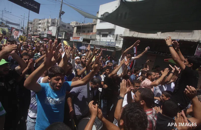 Palestinians hold up Egyptian national flags and posters of ousted Egyptian President Mohamed Morsi, during a demonstration to support Morsi and denounce Syria's President Bashar al-Assad, in Al-Nusirat refugee camp in c...