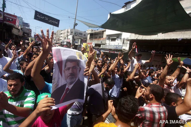 Palestinians hold up Egyptian national flags and posters of ousted Egyptian President Mohamed Morsi, during a demonstration to support Morsi and denounce Syria's President Bashar al-Assad, in Al-Nusirat refugee camp in c...