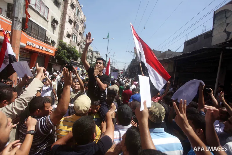 Palestinians hold up Egyptian national flags and posters of ousted Egyptian President Mohamed Morsi, during a demonstration to support Morsi and denounce Syria's President Bashar al-Assad, in Al-Nusirat refugee camp in c...
