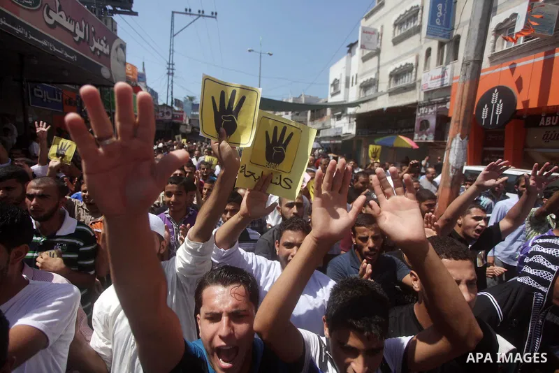 Palestinians hold Egyptian national flags, posters of ousted Egyptian President Mohamed Morsi and logos of four fingers, during a demonstration to support Morsi and denounce Syria's President Bashar al-Assad, in Al-Nusir...