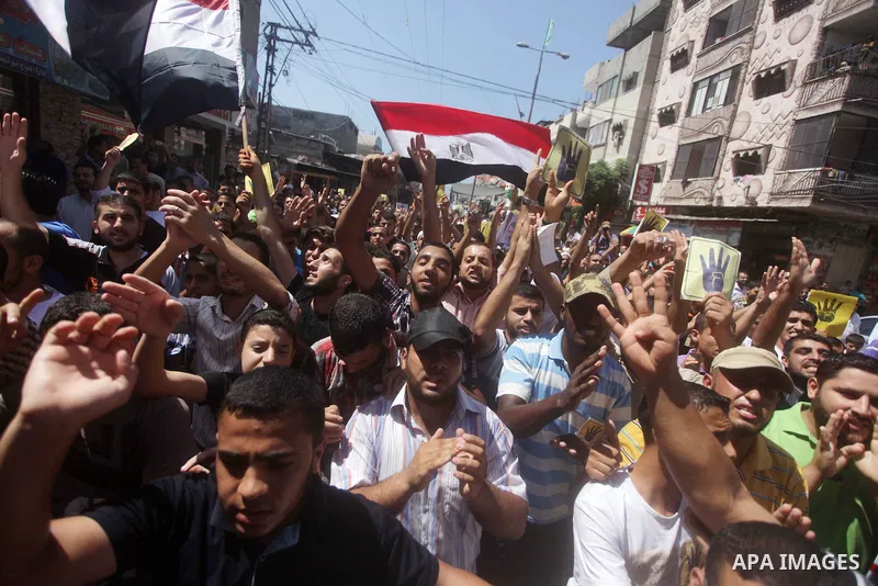 Palestinians hold up Egyptian national flags and posters of ousted Egyptian President Mohamed Morsi, during a demonstration to support Morsi and denounce Syria's President Bashar al-Assad, in Al-Nusirat refugee camp in c...