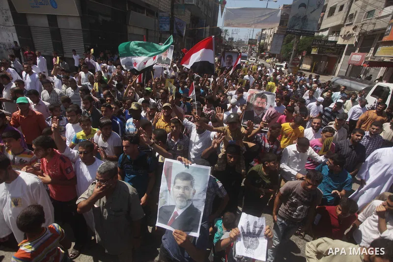 Palestinians hold up Egyptian national flags and posters of ousted Egyptian President Mohamed Morsi, during a demonstration to support Morsi and denounce Syria's President Bashar al-Assad, in Al-Nusirat refugee camp in c...