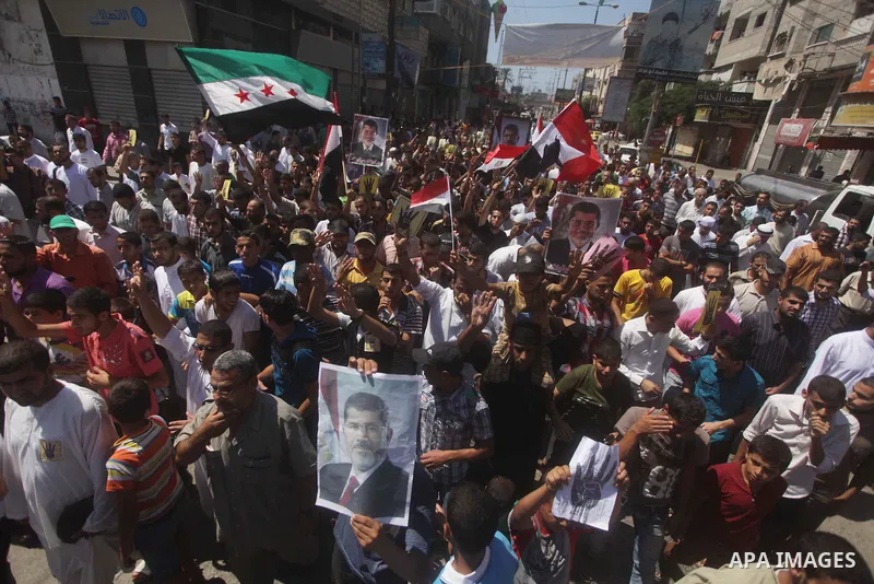 Palestinians hold up Egyptian national flags and posters of ousted Egyptian President Mohamed Morsi, during a demonstration to support Morsi and denounce Syria's President Bashar al-Assad, in Al-Nusirat refugee camp in c...