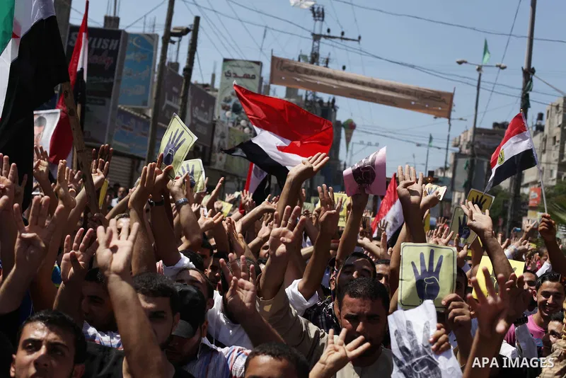 Palestinians hold Egyptian national flags, posters of ousted Egyptian President Mohamed Morsi and logos of four fingers, during a demonstration to support Morsi and denounce Syria's President Bashar al-Assad, in Al-Nusir...
