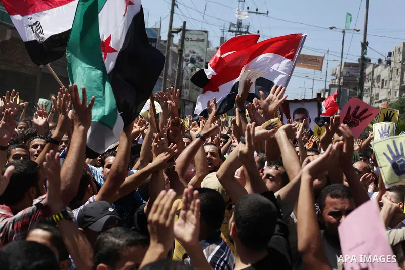 Palestinians hold Egyptian national flags, posters of ousted Egyptian President Mohamed Morsi and logos of four fingers, during a demonstration to support Morsi and denounce Syria's President Bashar al-Assad, in Al-Nusir...