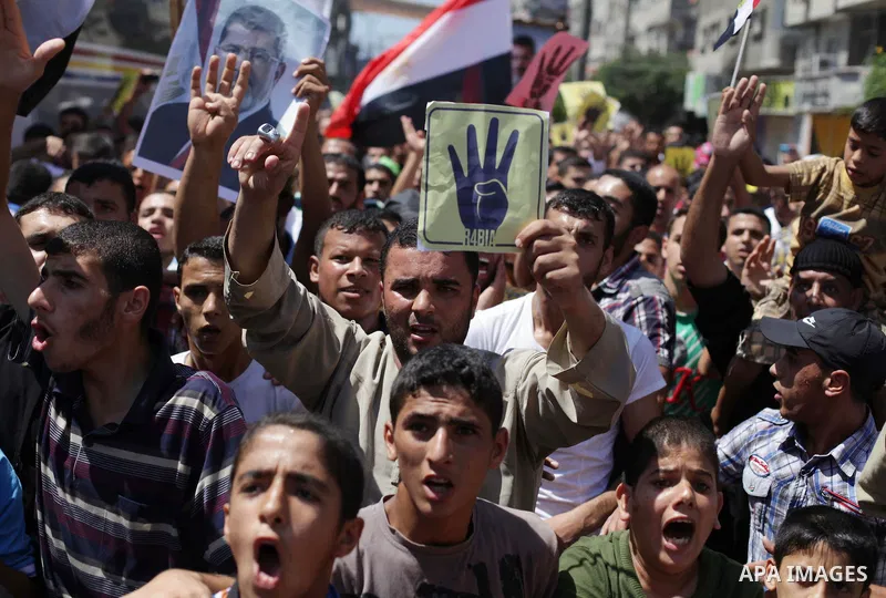 Palestinians hold Egyptian national flags, posters of ousted Egyptian President Mohamed Morsi and logos of four fingers, during a demonstration to support Morsi and denounce Syria's President Bashar al-Assad, in Al-Nusir...
