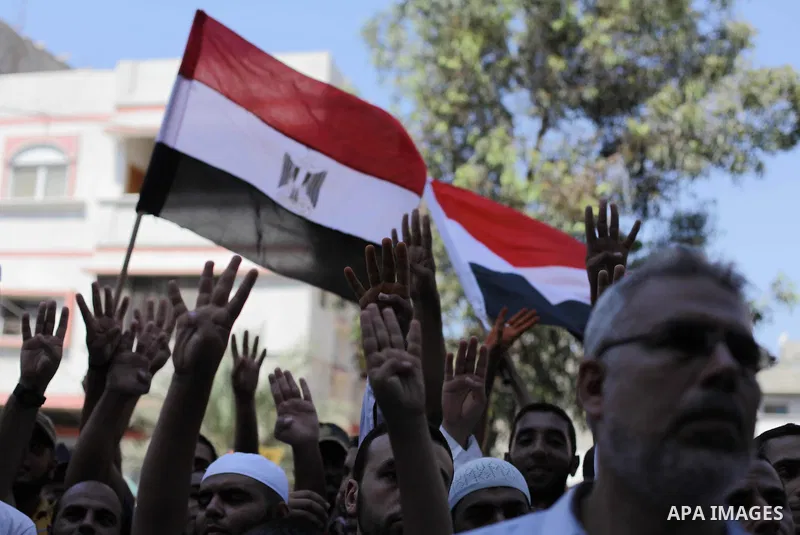 Palestinians hold Egyptian national flags, posters of ousted Egyptian President Mohamed Morsi and logos of four fingers, during a demonstration to support Morsi and denounce Syria's President Bashar al-Assad, in Al-Nusir...