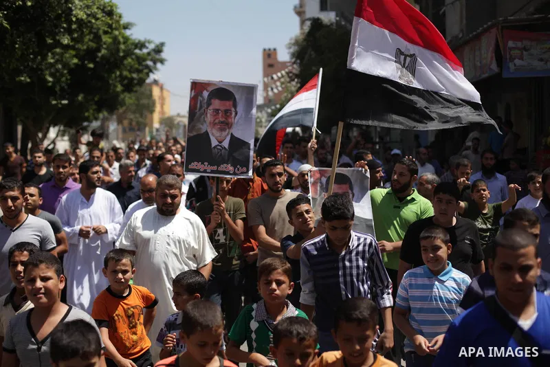 Palestinians hold up Egyptian national flags and posters of ousted Egyptian President Mohamed Morsi, during a demonstration to support Morsi and denounce Syria's President Bashar al-Assad, in Al-Nusirat refugee camp in c...
