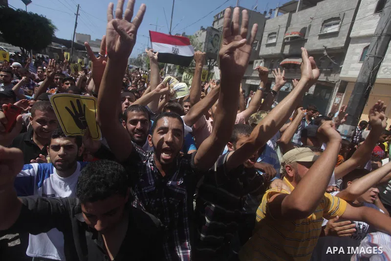 Palestinians hold Egyptian national flags, posters of ousted Egyptian President Mohamed Morsi and logos of four fingers, during a demonstration to support Morsi and denounce Syria's President Bashar al-Assad, in Al-Nusir...