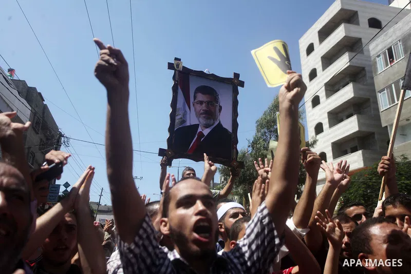 Palestinians hold Egyptian national flags, posters of ousted Egyptian President Mohamed Morsi and logos of four fingers, during a demonstration to support Morsi and denounce Syria's President Bashar al-Assad, in Al-Nusir...
