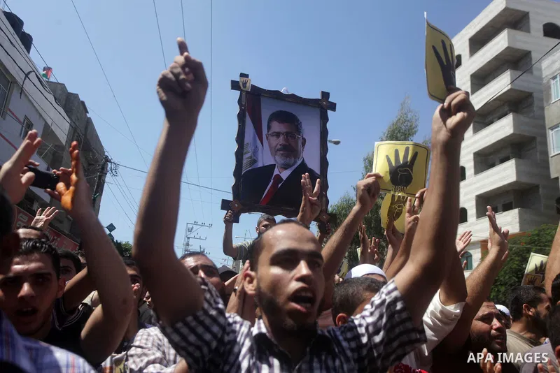 Palestinians hold Egyptian national flags, posters of ousted Egyptian President Mohamed Morsi and logos of four fingers, during a demonstration to support Morsi and denounce Syria's President Bashar al-Assad, in Al-Nusir...