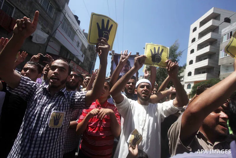 Palestinians hold Egyptian national flags, posters of ousted Egyptian President Mohamed Morsi and logos of four fingers, during a demonstration to support Morsi and denounce Syria's President Bashar al-Assad, in Al-Nusir...