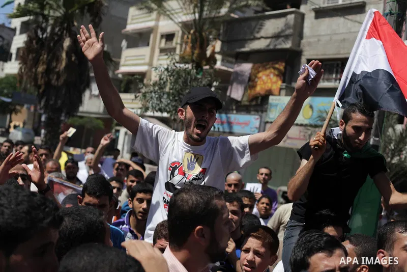 Palestinians hold Egyptian national flags, posters of ousted Egyptian President Mohamed Morsi and logos of four fingers, during a demonstration to support Morsi and denounce Syria's President Bashar al-Assad, in Al-Nusir...