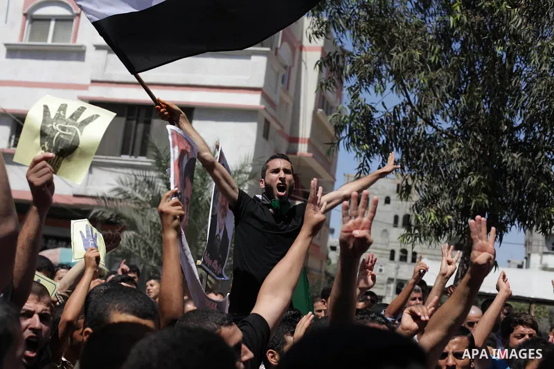 Palestinians hold Egyptian national flags, posters of ousted Egyptian President Mohamed Morsi and logos of four fingers, during a demonstration to support Morsi and denounce Syria's President Bashar al-Assad, in Al-Nusir...