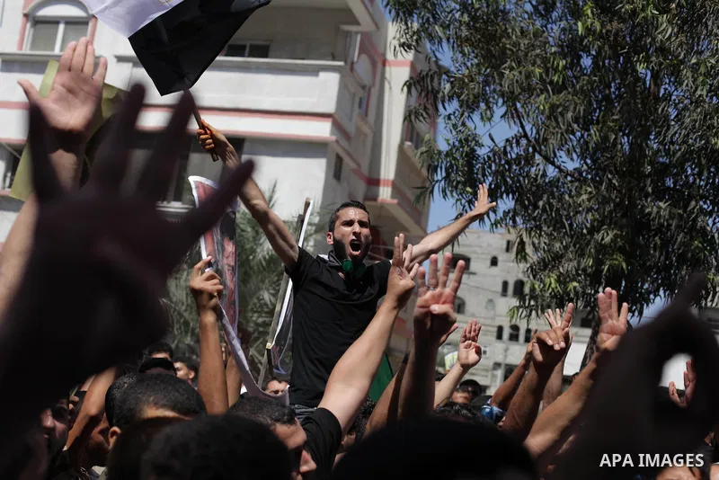 Palestinians hold Egyptian national flags, posters of ousted Egyptian President Mohamed Morsi and logos of four fingers, during a demonstration to support Morsi and denounce Syria's President Bashar al-Assad, in Al-Nusir...
