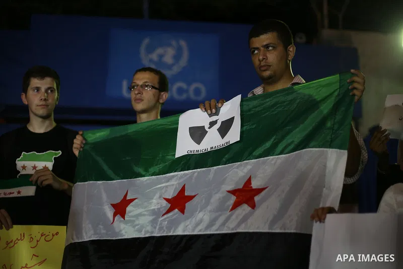 Palestinians hold syrian revolution flags during a protest against Syria's President Bashar al-Assad in front of the U.N. headquarters in Gaza City August 23, 2013. U.N. Secretary-General Ban Ki-moon said on Friday he in...