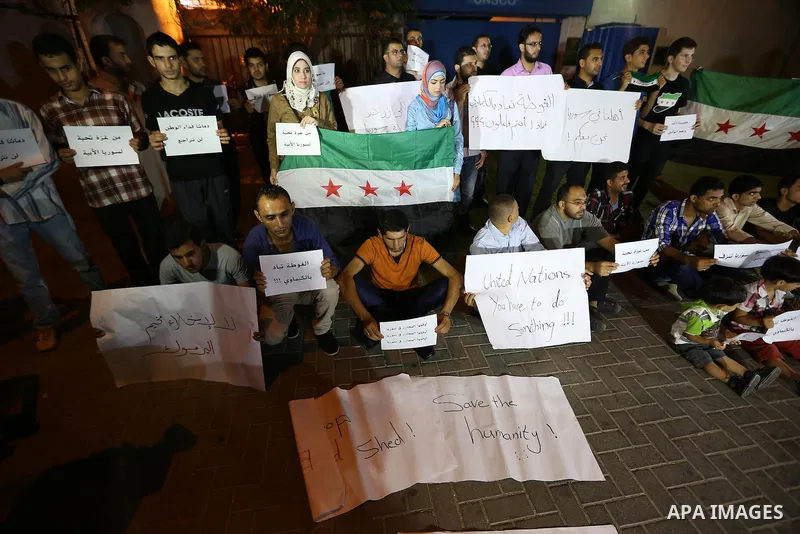 Palestinians hold syrian revolution flags during a protest against Syria's President Bashar al-Assad in front of the U.N. headquarters in Gaza City August 23, 2013. U.N. Secretary-General Ban Ki-moon said on Friday he in...
